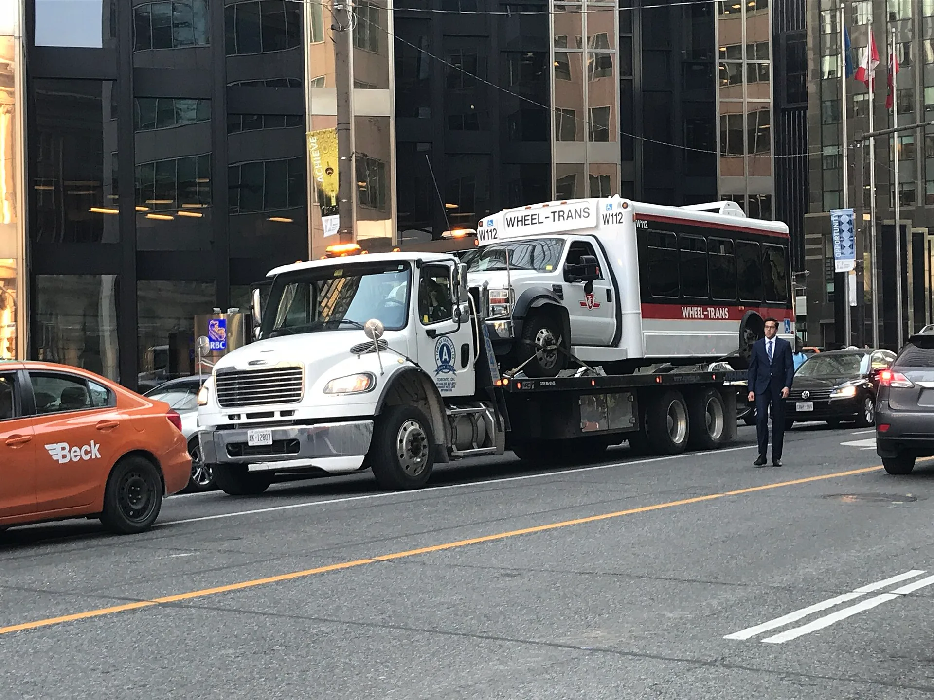 Wheel-Trans vehicle W112 (112) being lifted by a Freightliner tow truck, AK 12807. Towing company equipment: a reviewer's notes