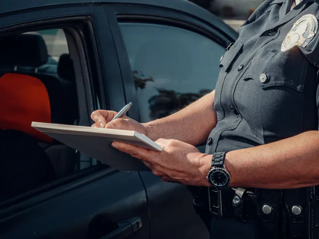 Close-up of a police officer writing a ticket by a car window. Law enforcement scene. 5 things about towing company sales worth your time