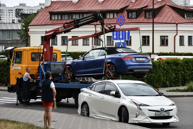 Towing a blue Audi convertible in a bustling city street. Towing company systems and KPIs for owners in 2027
